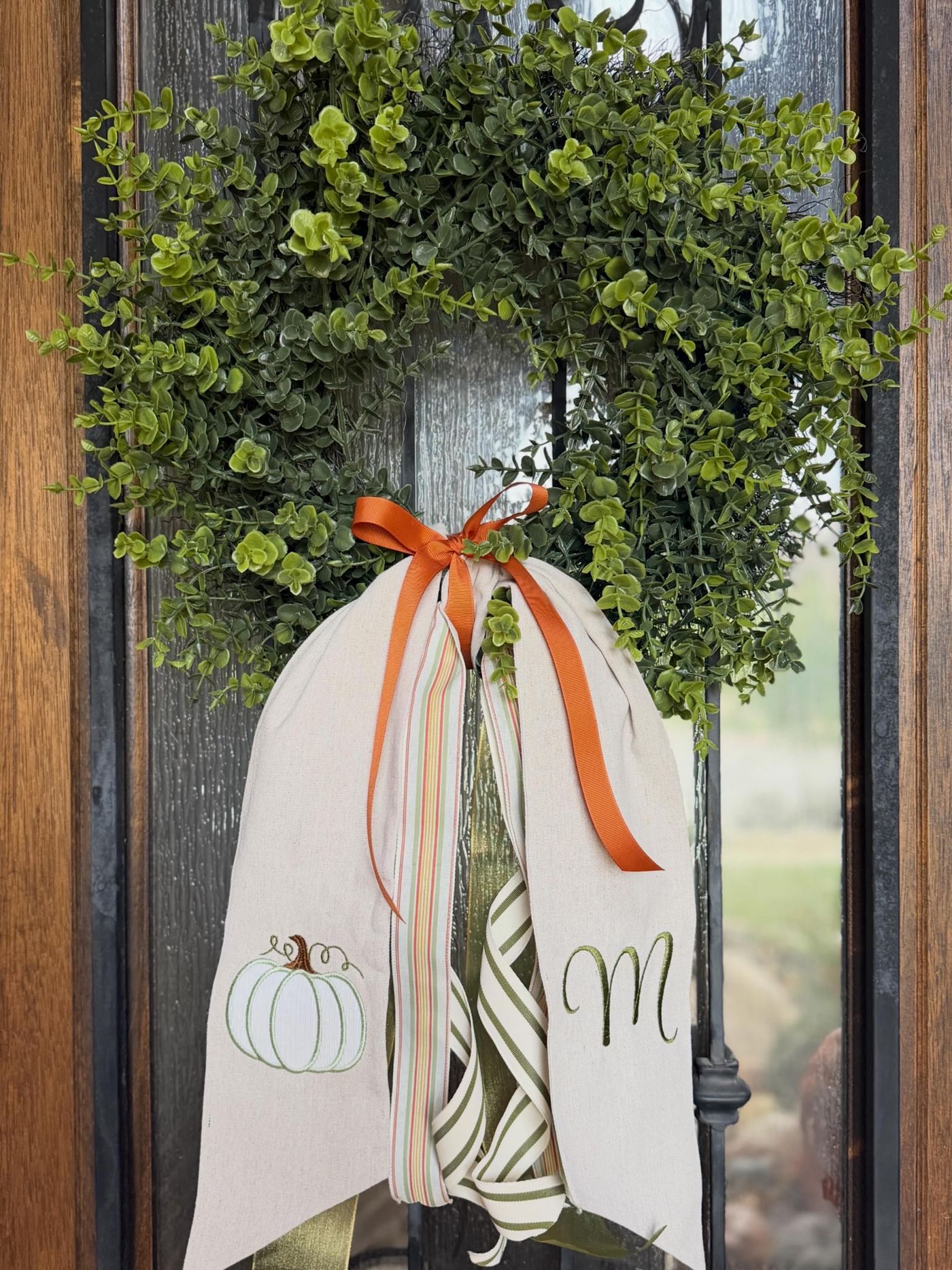 Eucalyptus wreath with an orange bow on a front door